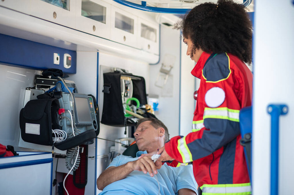 Ambulance physician placing the pulse oximeter on the fingertip of a patient lying on the gurney - Foto, Imagen