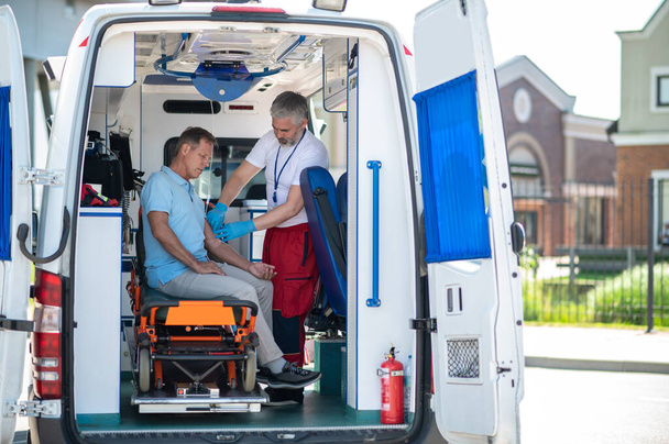 Ambulance lékař zajištění intravenózní katetr v žíle pacienta s lékařskou lepicí páskou - Fotografie, Obrázek