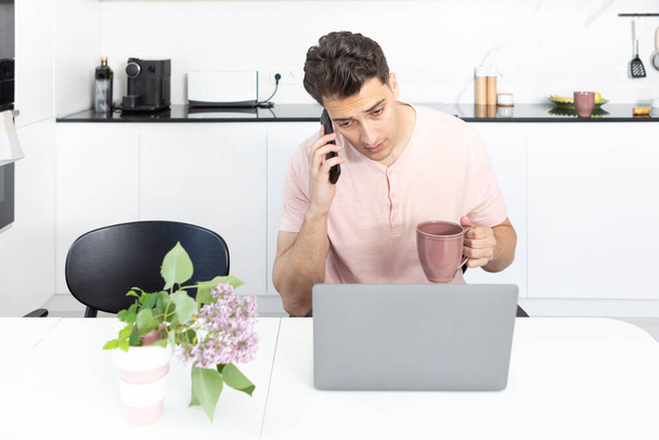 若いビジネスマンがノートパソコンで働いて家でお茶を飲む。遠くの仕事の概念 - 写真・画像