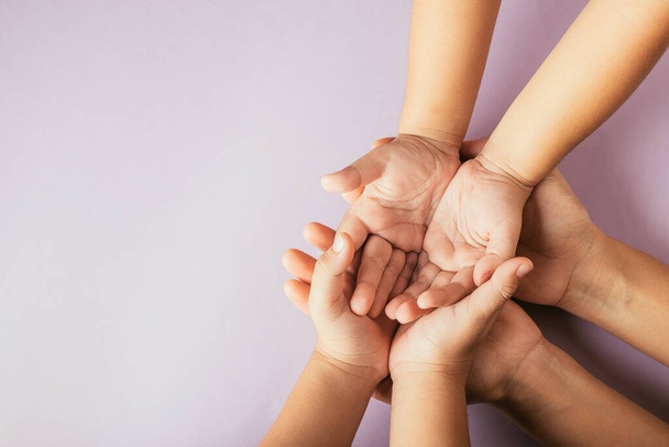 Closeup top view family hands stack palms studio shot isolated on purple background, parents and kid holding empty free space on hand together, Gesture sign of support and love, Family and parents day - Foto, afbeelding
