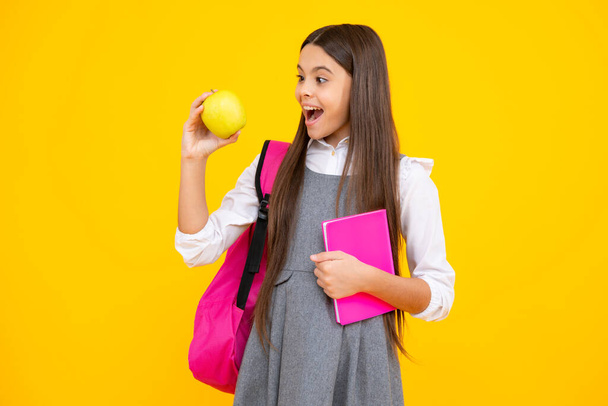 Excited face. School girl hold copybook and book on yellow isolated studio background. School and education concept. Teenager girl in school uniform. Amazed expression, cheerful and glad - Valokuva, kuva