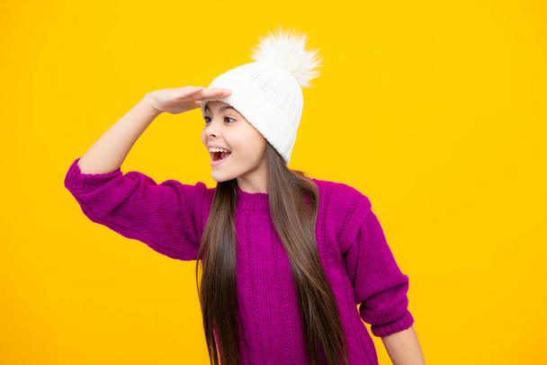 Teenager girl with winter hat over isolated yellow background. Winter christmas holidays, new year mood. Kids warm clothes - 写真・画像