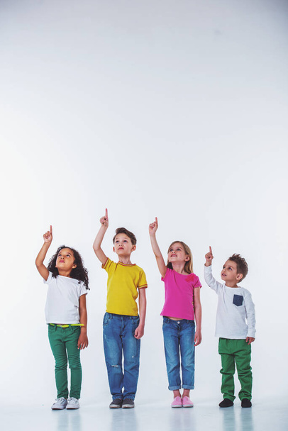 Ολόσωμο πορτρέτο των χαριτωμένα μικρά παιδιά σε casual ρούχα που αναζητούν και δείχνουν επάνω, απομονώνονται σε λευκό φόντο - Φωτογραφία, εικόνα