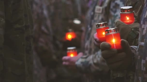 Пам'ятний день, щоб ми не забули. День пам'яті зі свічками. Запалюються пам'ятні свічки. Українські солдати у військовій формі з червоними свічками. Служителі на військовому параді. - Кадри, відео