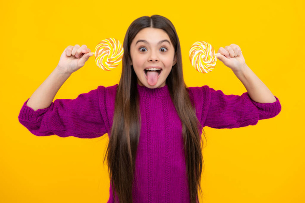 Excited face. Teen girl hold lollipop caramel on yellow background, candy shop. Teenager with sweets suckers. Amazed expression, cheerful and glad - Фото, изображение