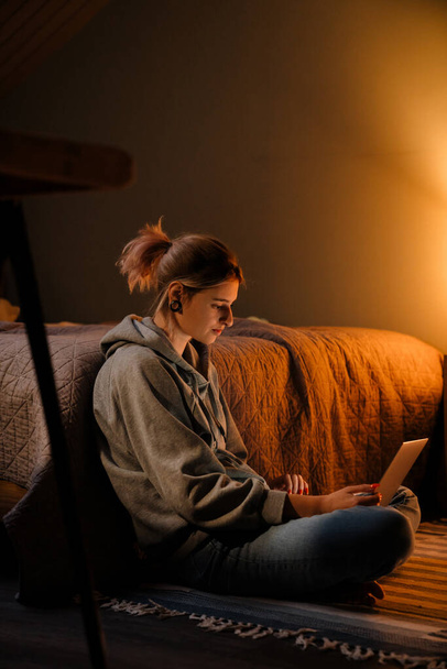 White girl with tunnel rings using laptop while sitting on floor at home - Fotografie, Obrázek