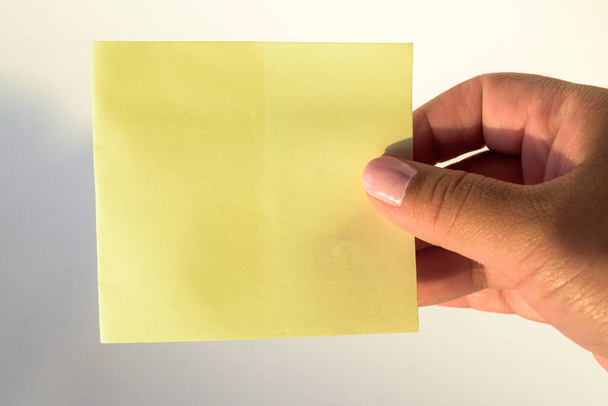 Nők kéz festett körmök tartó üres levél papír tiszta fehér háttér. - Fotó, kép