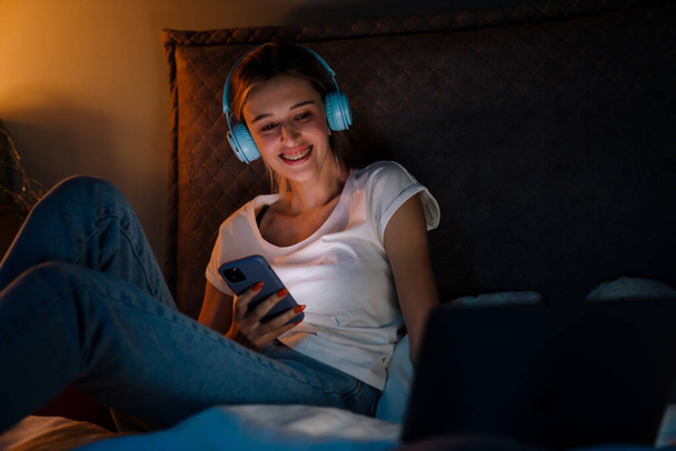 White girl laughing while listening music and using gadgets at home - Foto, afbeelding