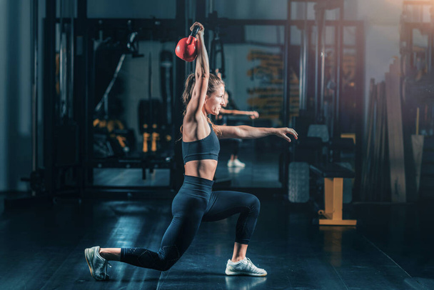 Woman Making Lunges with Kettlebell Over the Head. - Photo, Image