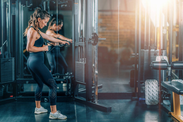 Женщина, делающая упражнения на тренажере в спортзале - Фото, изображение