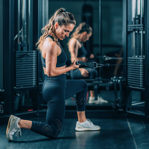 Женщина, делающая упражнения на тренажере в спортзале - Фото, изображение