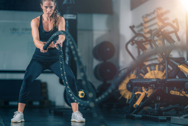 Entraînement d'agilité, femme faisant de l'exercice avec corde dans une salle de gym.  - Photo, image