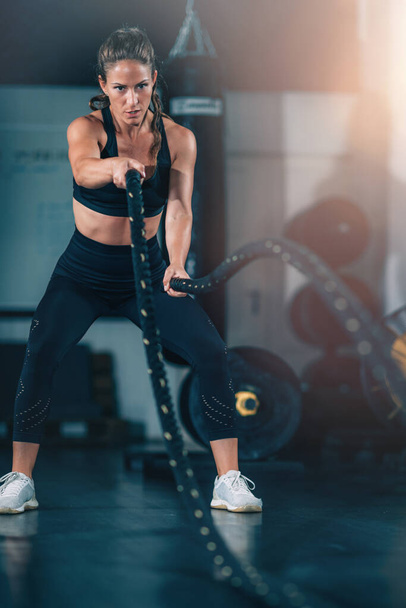 Entrenamiento de agilidad, mujer haciendo ejercicio con cuerda en un gimnasio.  - Foto, Imagen