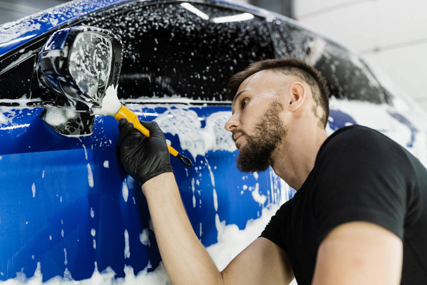 Lavaggio delle spazzole a mano dello specchio laterale dell'auto con schiuma nel servizio di dettagli dell'auto. Lavanderia auto lavaggi corpo auto - Foto, immagini