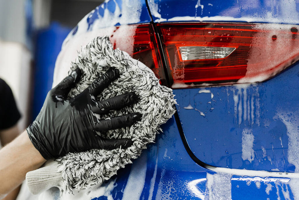 Миття рук за допомогою мікрофібри з кузовом піни автомобіля в гаражі. Автомийка робить ручне миття піни в автосервісі
 - Фото, зображення