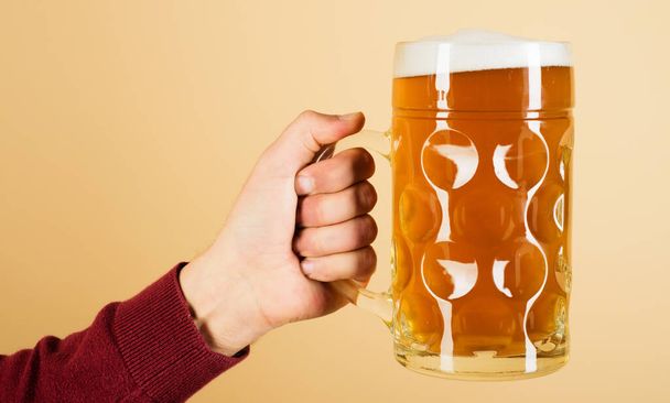 Man hand with mug of lager beer. Oktoberfest drink. Alcohol, party, degustation and holiday concept - 写真・画像