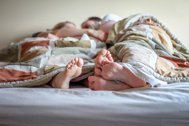 Yatakta Ayakları Battaniyenin Altında Sarılmış Uzanmış Bir Çift - Fotoğraf, Görsel