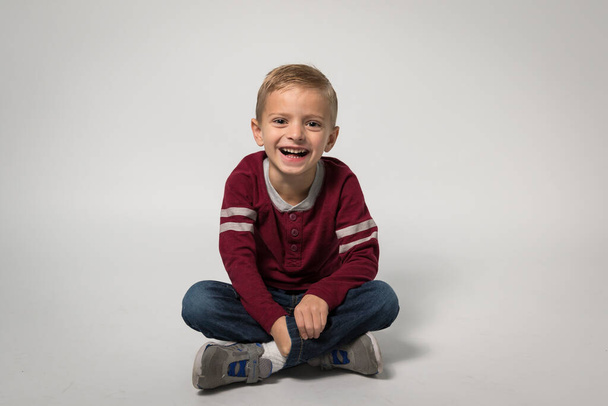 Malý chlapec sedící a smějící se kameře - Fotografie, Obrázek