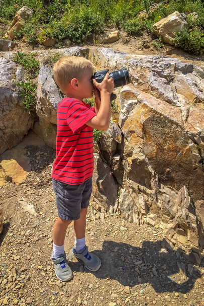 荒野でデジタル一眼レフカメラで写真を撮る男の子 - 写真・画像