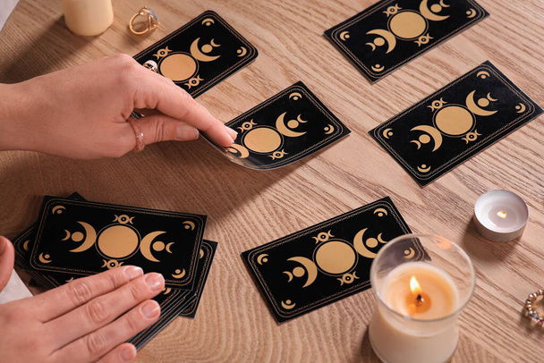 Soothsayer predicting future with tarot cards at wooden table, closeup - Fotó, kép
