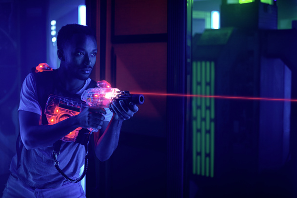 laser tag game player shooting light gun science fiction vest in black light - 写真・画像