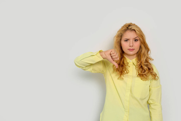 Dissatisfied young woman showing thumb down gesture on white background. Space for text - Фото, зображення