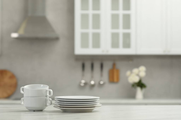 Clean dishware on white table in kitchen, space for text - Foto, imagen