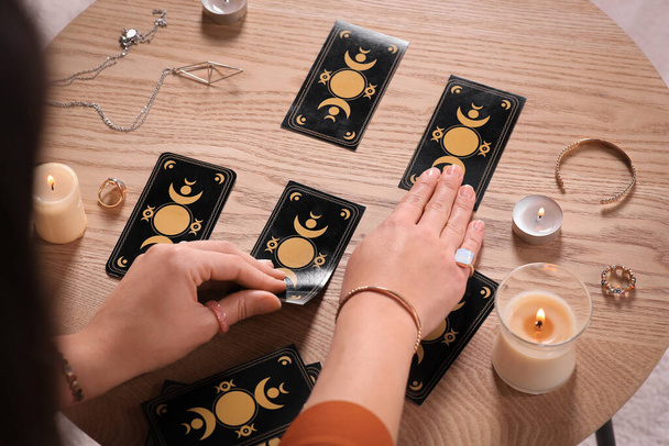 Soothsayer predicting future with tarot cards at wooden table, closeup - Фото, изображение