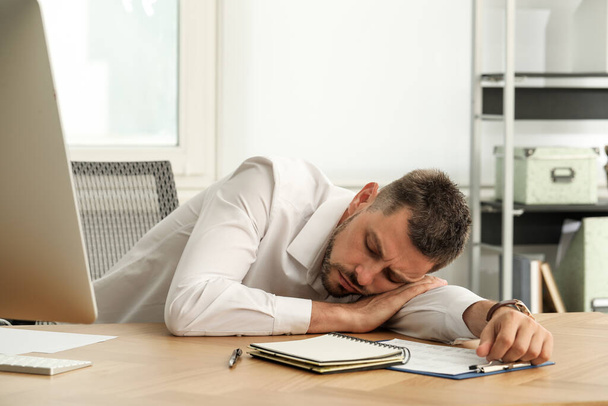 Tired man sleeping at workplace in office - Fotografie, Obrázek