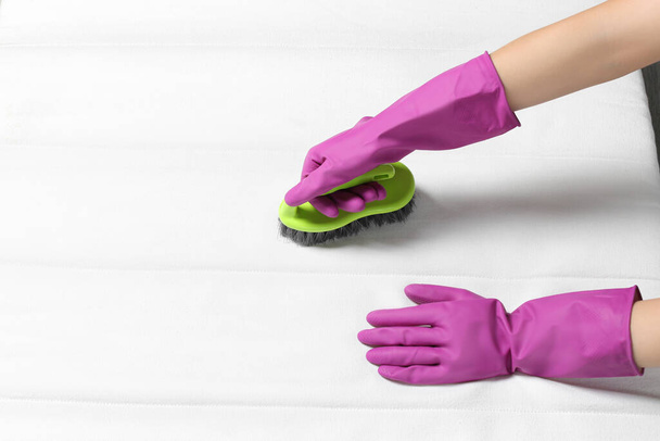 Woman in purple gloves cleaning white mattress with brush, closeup. Space for text - Valokuva, kuva
