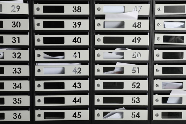 Metal mailboxes with keyholes, numbers and receipts as background - Foto, afbeelding