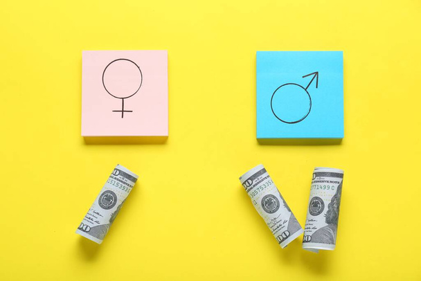 Gender pay gap. Paper notes with symbols and dollar banknotes on yellow background, flat lay - Foto, Imagen