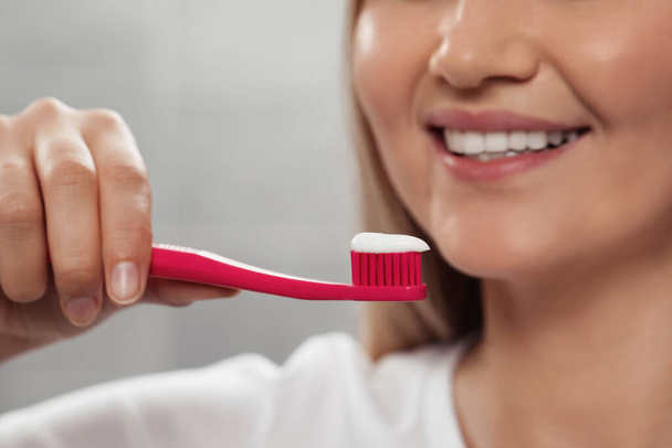 Woman holding brush with toothpaste in bathroom, closeup - Foto, Imagem