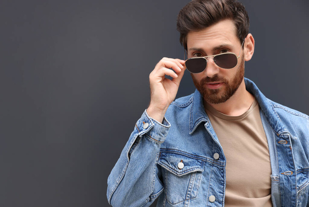 Portrait of handsome bearded man with sunglasses on grey background. Space for text - Photo, Image
