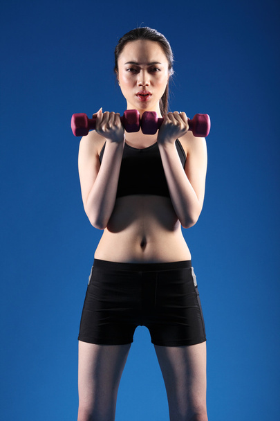 Fit young oriental woman lifting exercise weights - Foto, afbeelding