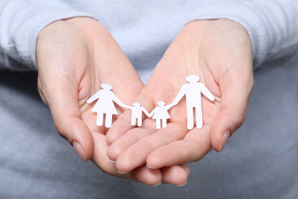 Woman holding paper family figures, closeup. Insurance concept - Фото, изображение