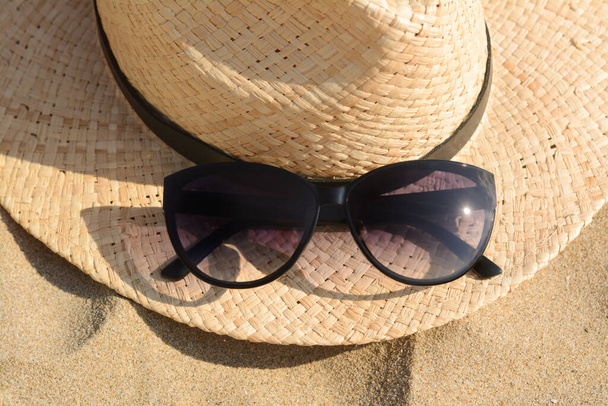 Hat with beautiful sunglasses on sand, closeup - Valokuva, kuva