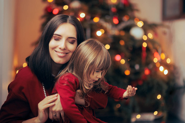 Happy Mom Holding her Daughter Enjoying Christmas Holiday - Photo, Image