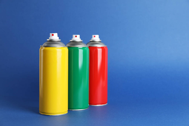 Colorful cans of spray paints on blue background. Space for text - 写真・画像