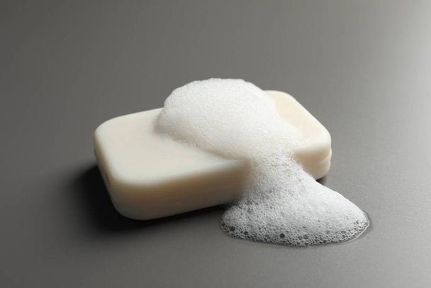 Soap with fluffy foam on grey background - Фото, изображение