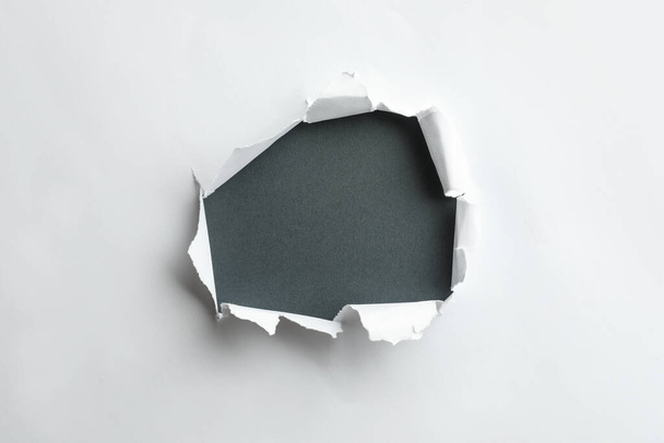 Hole in white paper on black background - Фото, изображение