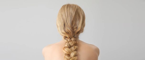 Rubia joven con cabello trenzado sobre fondo claro - Foto, Imagen