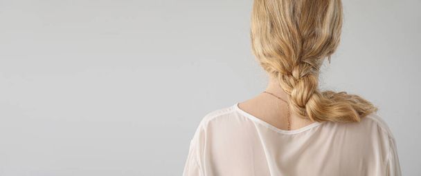 Νεαρή ξανθιά με πλεγμένα μαλλιά σε ανοιχτό φόντο με χώρο για κείμενο - Φωτογραφία, εικόνα