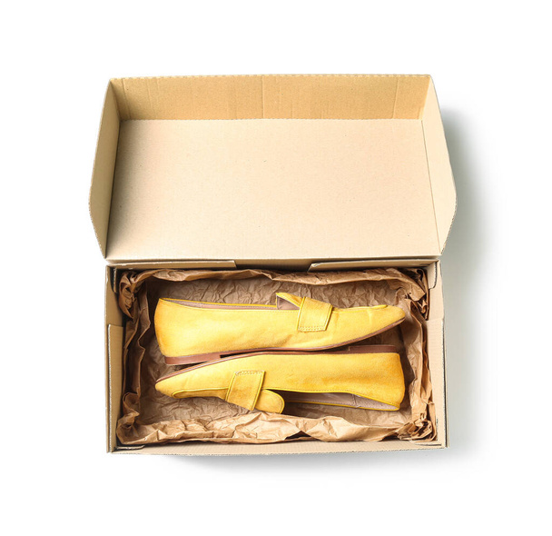 Caja de cartón con mocasines amarillos sobre fondo blanco - Foto, imagen