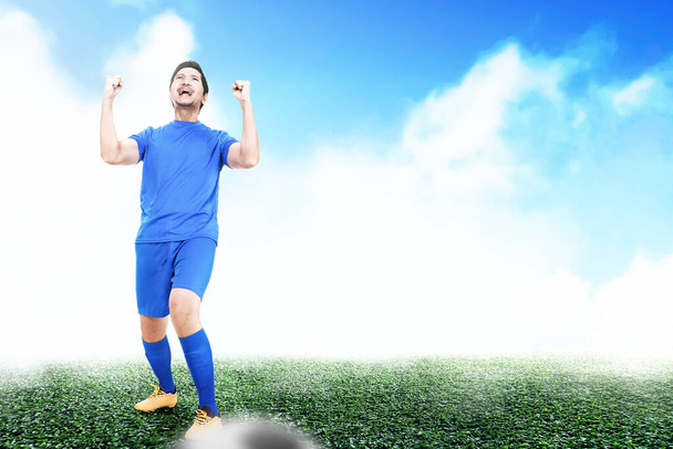 Asian football player man in a blue jersey celebrates the victory on the football field - Valokuva, kuva
