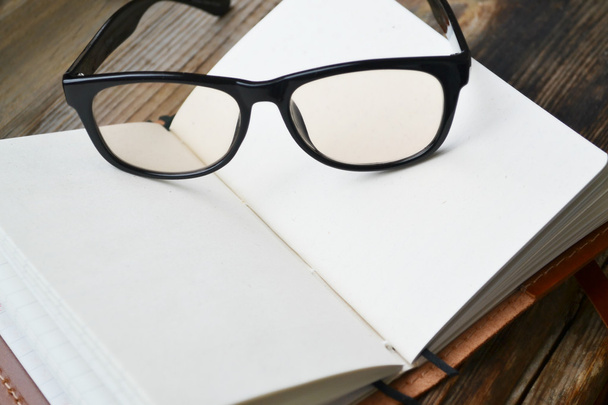 Un carnet rétro vide avec vieux papier, lunettes et housse en cuir
 - Photo, image