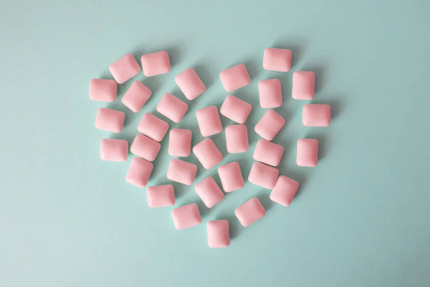 Pink bubble gum in the shape of a heart on a blue background - Photo, image