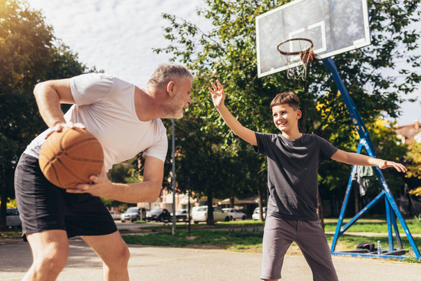 Ώριμος που παίζει μπάσκετ με το γιο του. - Φωτογραφία, εικόνα