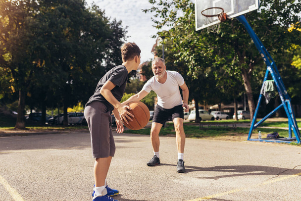 Reifer Mann spielt Basketball mit seinem Sohn - Foto, Bild