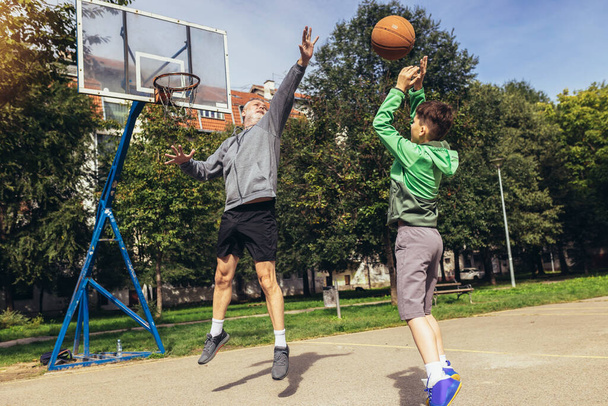 Mature man playing basketball with his son - Photo, Image